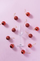 Minimal New Year party concept with red Christmas baubles and empty glass. Flat lay.