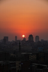 Fototapeta na wymiar Orange and yellow open skies. Sunset over the city of Cairo in Egypt. Silhouette of the buildings in the metropolis. Neighborhood view of the cityscape.