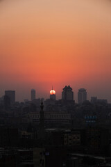 Obraz premium Orange and yellow open skies. Sunset over the city of Cairo in Egypt. Silhouette of the buildings in the metropolis. Neighborhood view of the cityscape.
