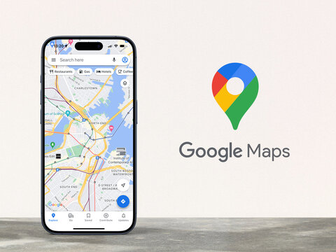 modern smartphone displaying map view of Google Maps, standing on a stone desk in front of a gray wall with the Google Maps logo, Alphabet, navigation, route, cartography