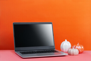 Laptop on table with minimal autumn or fall season decor, orange color, seasonal business concept