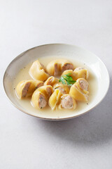 Traditional Catalan Christmas dish Escudella in white plate on table, stuffed pasta in meat broth, top view