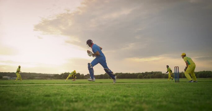 Two International Indian Teams Playing a Friendly Match of Cricket. Blue Team Batsman Hitting the Ball, Running to Other Side of the Pitch. Second Batter is Stopped When Yellow Team Hits the Wicket