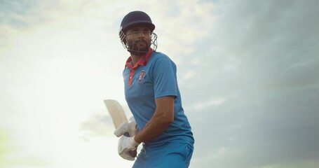 Portrait of an Athletic Indian Cricket Player Preparing to Strike the Ball with a Bat. Batter From a Blue Team Ready to Send the Ball to the Outfield. Low Angle Handheld Footage on a Cloudy Day
