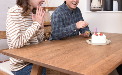 ケーキにロウソクを立てるカップル