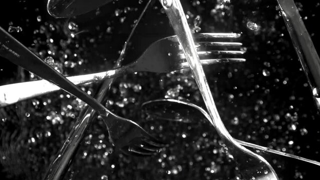 Cutlery flies up with splashes of water. View from above. Filmed on a high-speed camera at 1000 fps. High quality FullHD footage