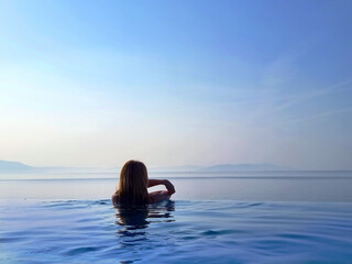 Fototapeta premium Portrait of a beautiful young woman relaxing in outdoor infinity swimming pool nearly sea beach in resort. vacation leisure wallpaper