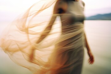 A beautiful woman in a dress at the beach at the golden hour. Shutter drag style photograph of a model dancing at the shore