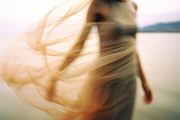 A beautiful woman in a dress at the beach at the golden hour. Shutter drag style photograph of a model dancing at the shore