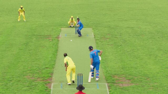 South Asian Cricket Bowler in Yellow and Green Uniform Running and Throwing the Ball on a Pitch. Professional Indian Teams Practicing Before a World Championship. Live Sports TV Broadcast