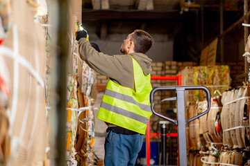 A man in a protective vest and gloves takes out a large cardboard box of things prepared for...