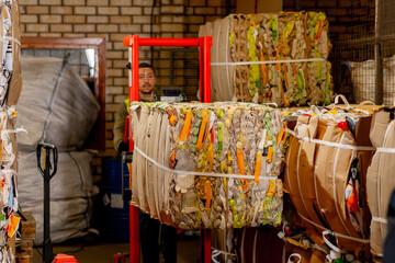 A worker using a stacker lifts and transports a cargo cardboard box with things for recycling at...