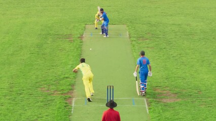 South Asian Cricket League Playing a Tournament. Blue Team Batter Successfully Strikes the Ball, But the Yellow Field Player Passes the Ball Just in Time. Sports TV Channel Broadcast