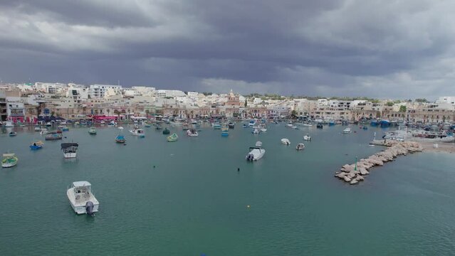 Aerial panoramic drone footage traditional eyed colorful boats (Luzzu) in the Harbor of Mediterranean fishing village, Marsaxlokk, Malta