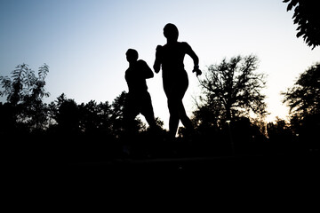 A fit couple jogging in the park during a late evening workout.