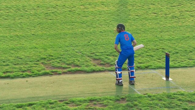 Portrait of a Professional Cricket Player in Blue Uniform and Protective Helmet Practicing to Hit the Ball During Training. Batsman Warming Up Before a Championship Match