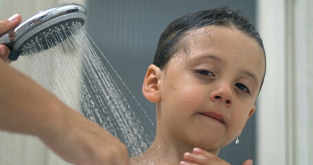 Mother Bathing Son with Shower i, close-up face of little boy underneath shower head