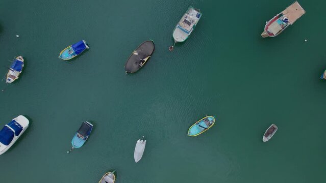 Aerial panoramic drone footage of traditional eyed colorful boats (Luzzu) in the Harbor of Mediterranean fishing village, Marsaxlokk, Malta