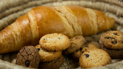 Chocolate chip cookies and croissants are placed in a wicker basket on a white cardboard background. Croissants on a white background. Chocolate chip cookies on a white background