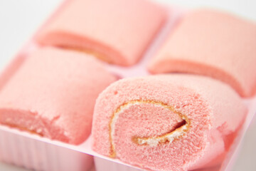Fototapeta premium Strawberry roll cake on white background. Rose strawberry cake placed on a plate