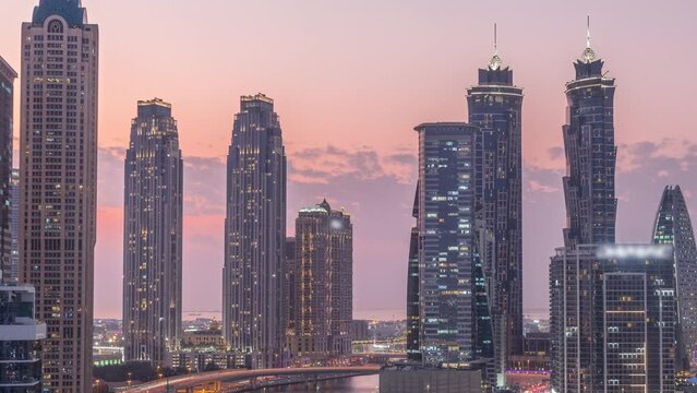 Cityscape with skyscrapers of Dubai Business Bay and water canal aerial day to night transition timelapse. Modern skyline with residential and office towers on waterfront after sunset
