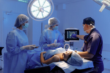 A male and woman surgeon are working together to prepare a patient for surgery in a hospital room