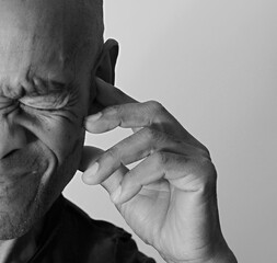 deaf man suffering from deafness and hearing loss on grey black background with people stock image...
