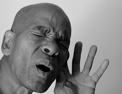 deaf man suffering from deafness and hearing loss on grey black background with people stock image stock photo	