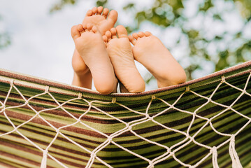 Feet of children, which swinging on hammock at summer.Kids relax,happy childhood