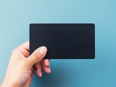 Male hand holding a black bank card on a blue background AI
