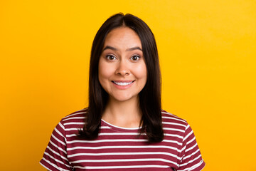 Photo of toothy beaming satisfied person with straight hairstyle wear striped t-shirt look at camera isolated on yellow background