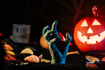 Terrible zombie hand climbs out grave. Creepy moment from undead life. Halloween