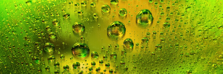 Drops of water banner. Abstract wet background. Colored macro texture of large and small drops. Rainbow gradient. Heavily textured image. Small depth of field. Selective focus