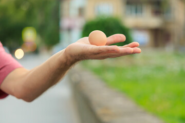 The guy's hand holds an egg. Selective focus on hands with blurred background