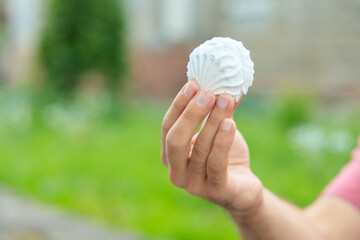 Guy's hand holds marshmallow, snack and fast food concept. Selective focus on hands with blurred...