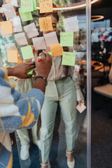 Diverse business professionals brainstorm and collaborate in a modern office. Sticky notes on a glass wall symbolize innovation and teamwork as they discuss growth, marketing, and problem-solving.