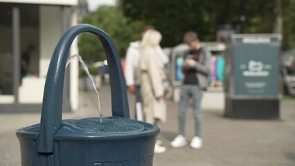 View of drinking fountain and out of focus shoppers in Kurfurstendamm, Charlottenburg, Berlin