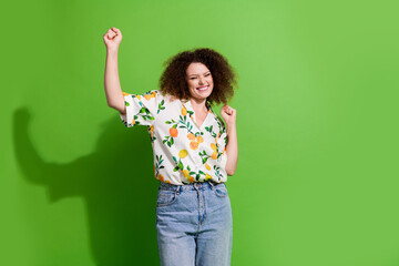 Photo of carefree lucky lady wear print shirt rising fists shouting yes isolated green color background