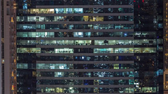 Office buildings windows illuminated at night timelapse. Glass architecture, corporate building at evening with glowing lights