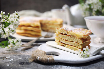 French cuisine. Matefaim. Stack of sweet Apple Pancakes, cup of tea and white spring flowers - 668701209