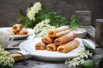 Fripons, French pastries. Apricot jam sweet puff pastry rolls and spring elderberry flowers - 668701236