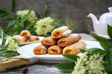 Fripons, French pastries. Apricot jam puff pastry rolls for summer tea and white flowers - 668701252