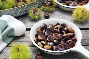 Close up of sweet chestnuts for frying in pan on wooden background - 668702052
