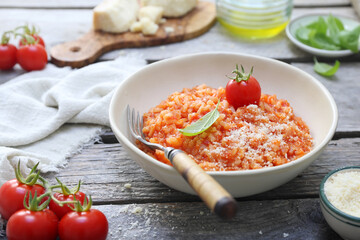 Italian cuisine. Plate of tomato risotto, olive oil, basil and cherry tomatoes - 668702054