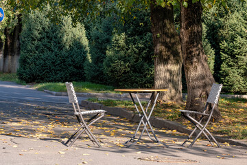 Free table in a street cafe under a tree in autumn.