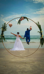 newlywed couple back to back, young caucasian woman in wedding dress, tall black man in suit jumping, heart shaped balloon