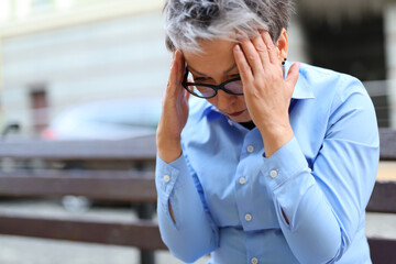 Senior woman, deeply saddened and in pain, coping with a debilitating headache in her home.