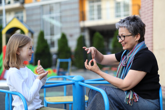 An intergenerational bond, senior and young - share the happiness of communicating through sign language in a colorful, joyful park setting