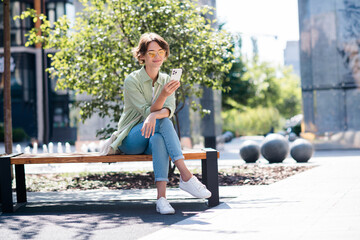 Photo of gorgeous adorable girl sitting on bench reading sms waiting friend meeting date spring...