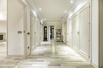 Large dressing room with access to a bedroom with fireplace and many built-in wardrobes with lacquered wooden doors and white oak parquet floors